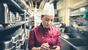 A female chef checks messages on her phone