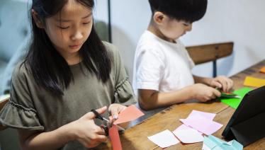 Siblings making origami at home