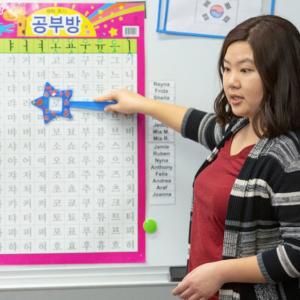 Teacher pointing to Korean chart in classroom