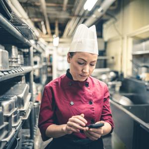 A female chef checks messages on her phone