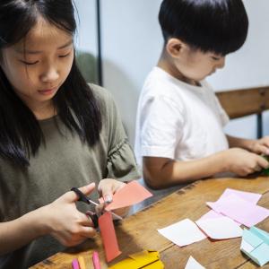 Siblings making origami at home