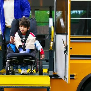 Boy in wheelchair using lift on school bus